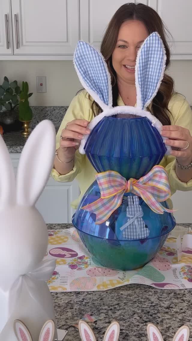 Woman holding a blue plastic Easter basket decorated with bunny ears and a bow.