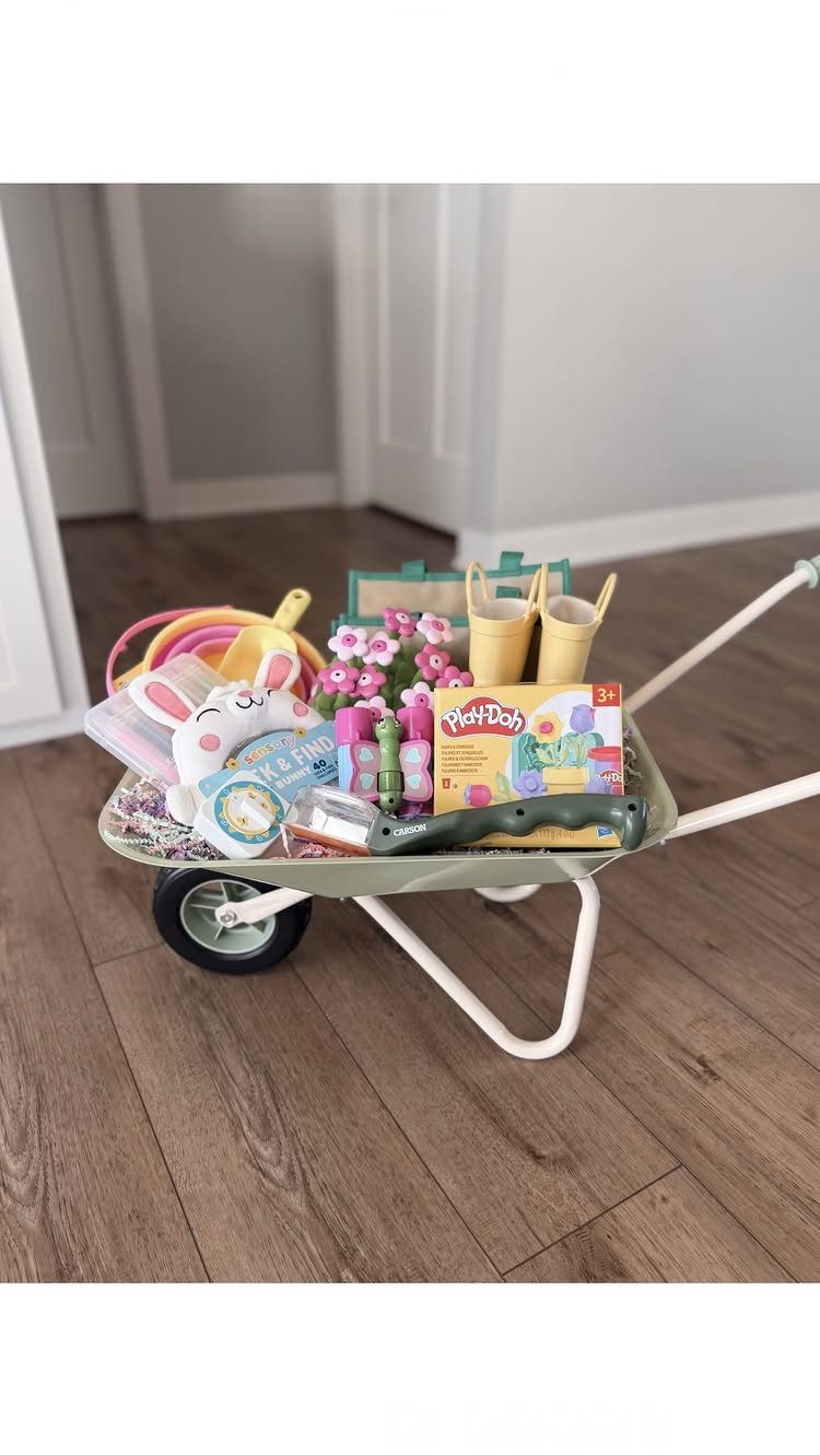 Toy wheelbarrow filled with Easter toys, a plush bunny, and colorful gifts.