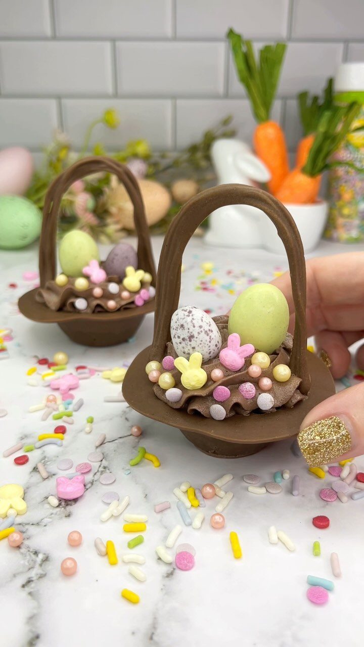 Chocolate Easter baskets filled with candy eggs and sprinkles on a marble surface.
