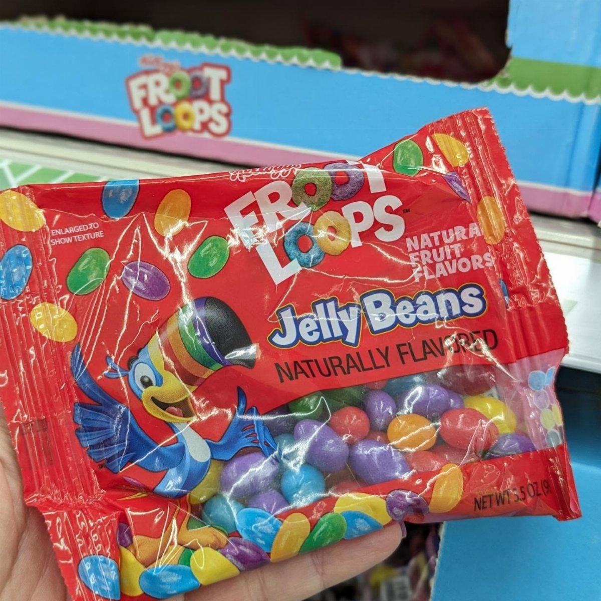 Froot Loops flavored jelly beans in a red bag held by a hand.