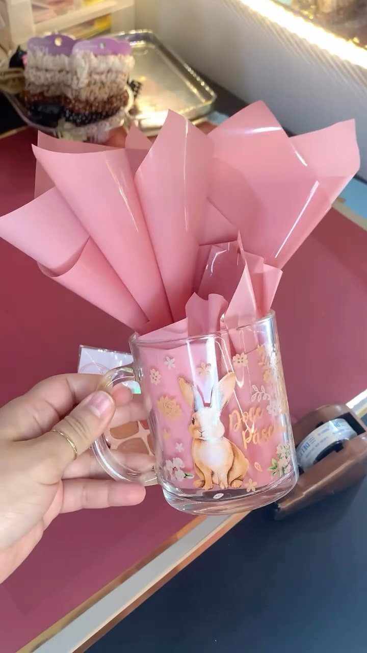 Clear glass mug with a bunny illustration filled with pink tissue paper.