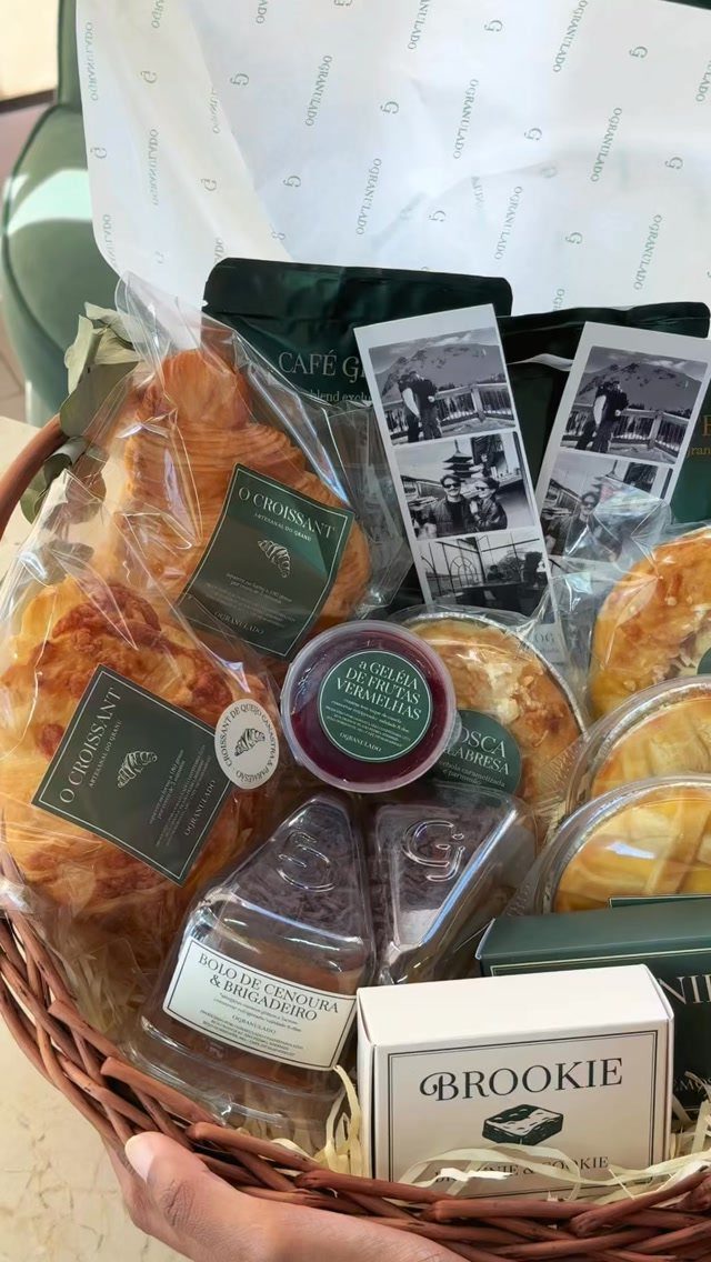 Wicker basket filled with packaged croissants, pastries, and a box of brookies.