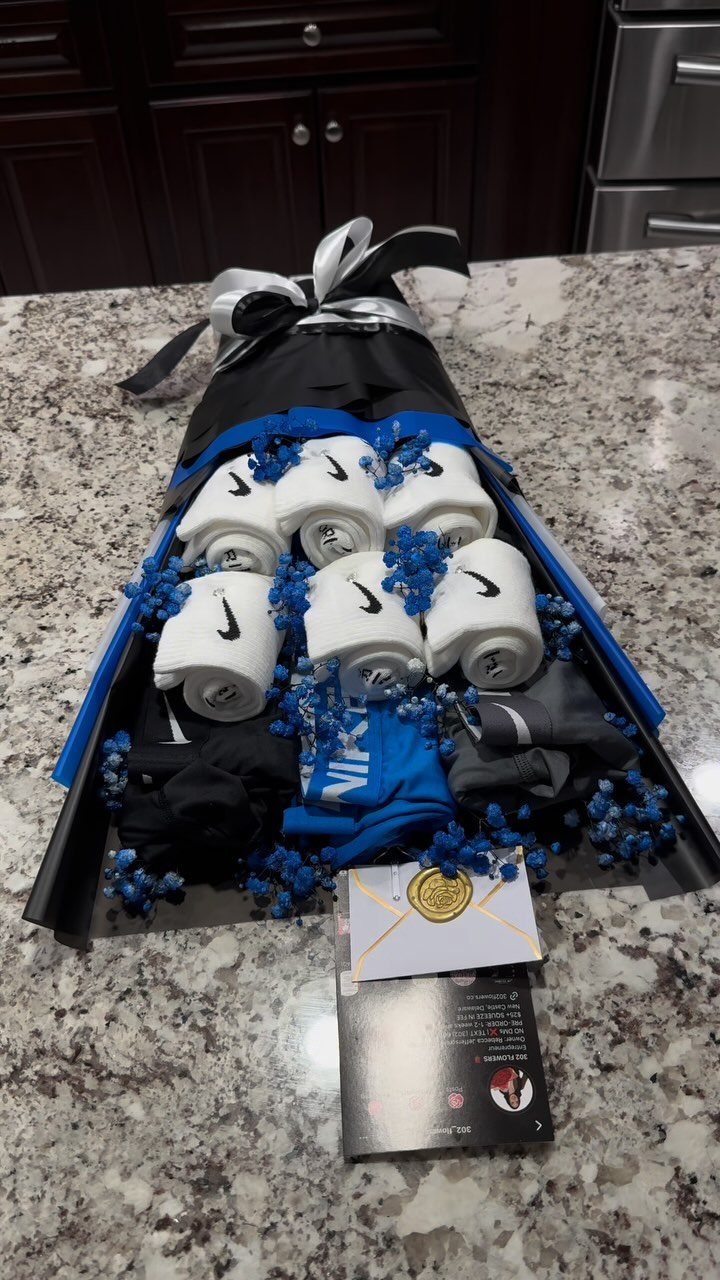 Gift bouquet with Nike socks and clothing wrapped in black and blue paper.