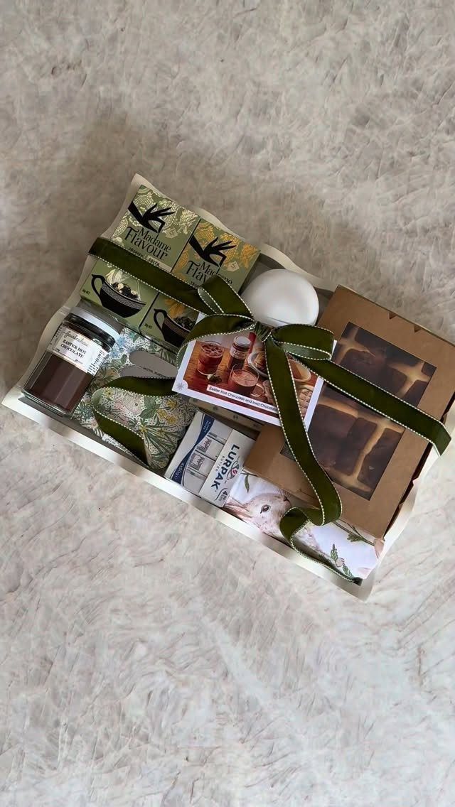 Gift box with assorted treats and a white egg tied with green ribbon.