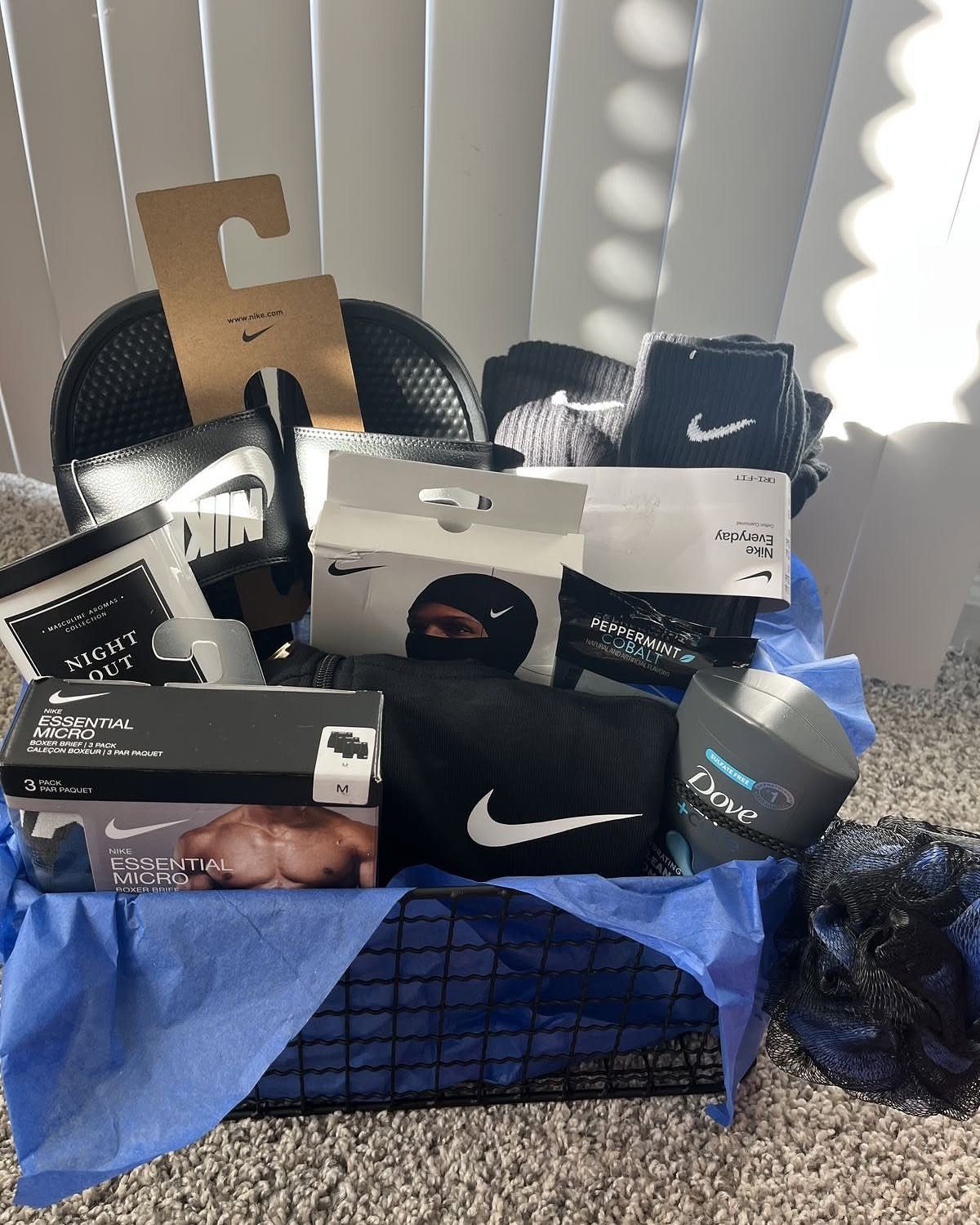 Black wire gift basket filled with Nike apparel, Dove soap, and blue tissue paper.
