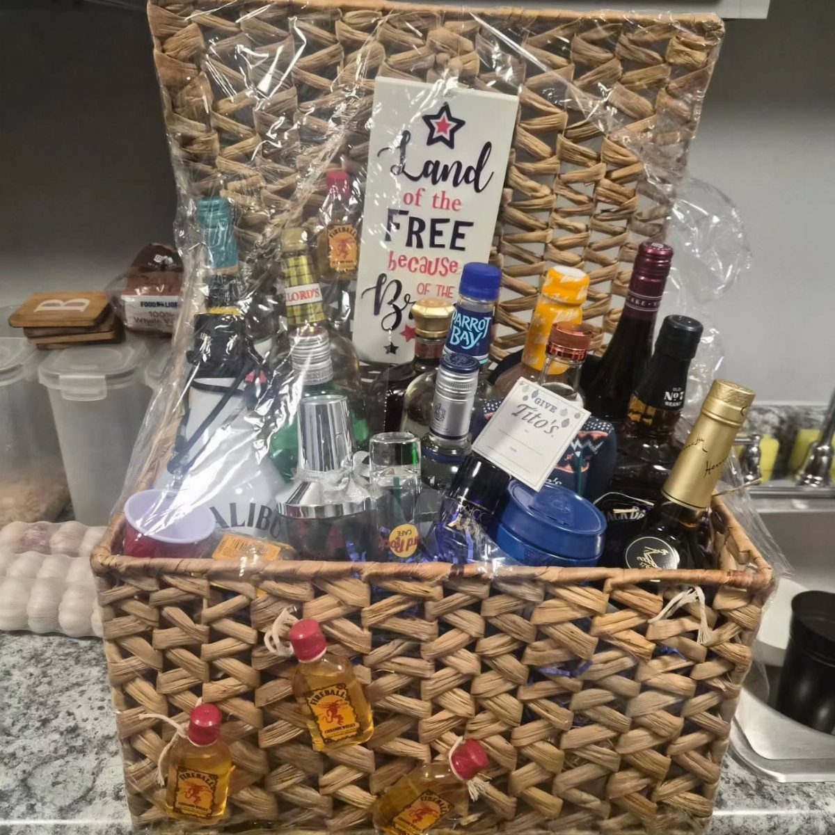 Wicker gift basket filled with various liquor bottles and a patriotic sign.