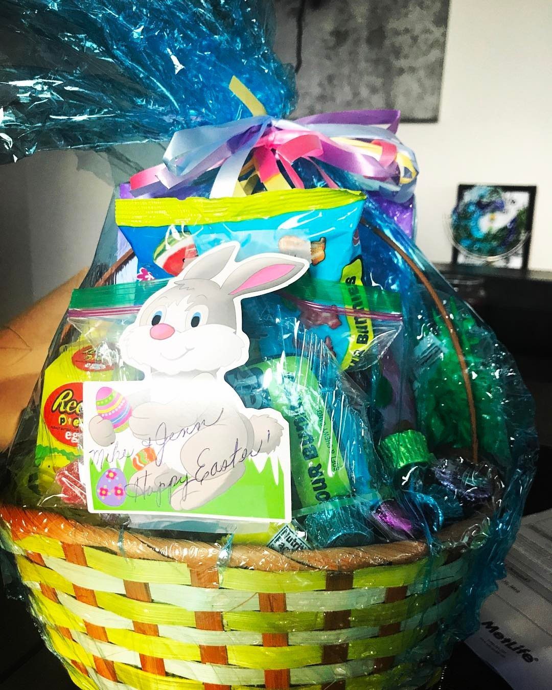 Easter basket filled with candy and snacks wrapped in blue cellophane with bunny card