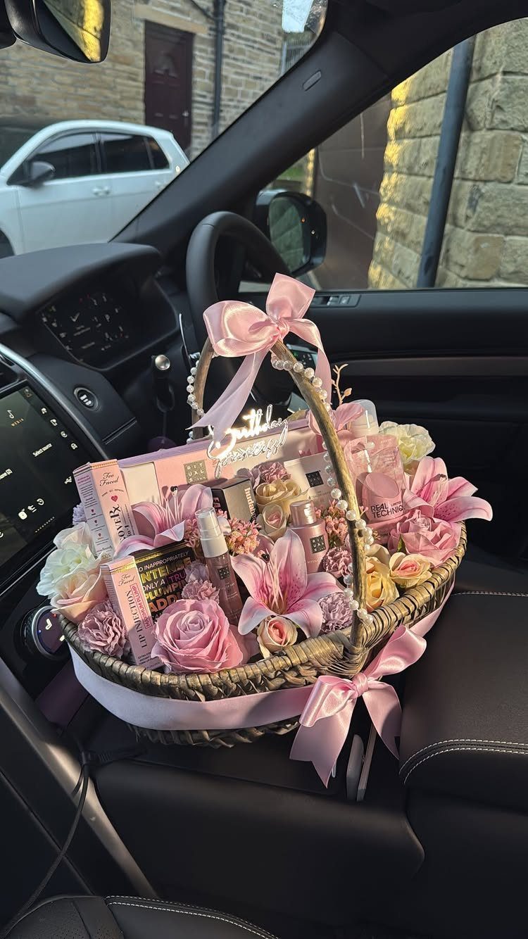 Woven gift basket with pink flowers and beauty products on a car seat