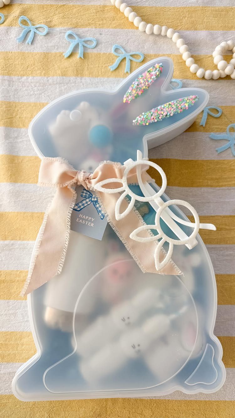 Bunny-shaped translucent container filled with Easter treats on a yellow striped background.