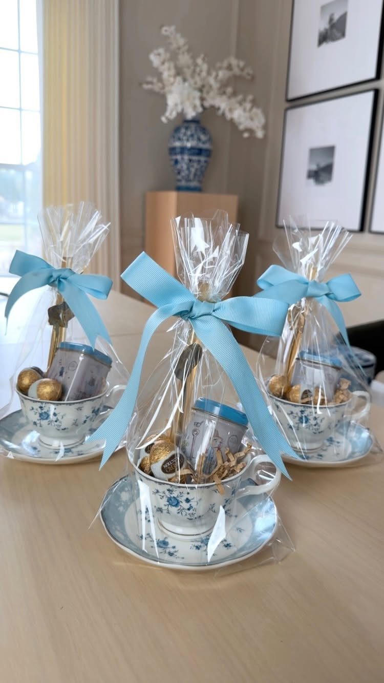 Three floral teacup gift sets wrapped in cellophane with light blue ribbons.