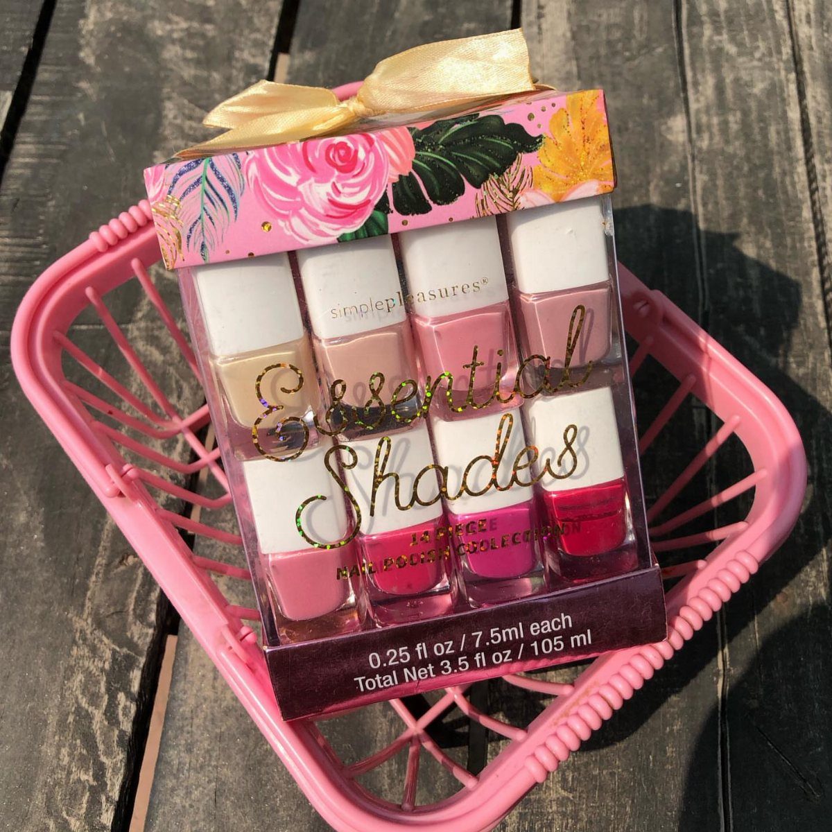 Pink wire basket holding a boxed set of pink and red nail polishes.
