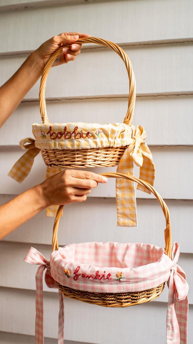 Two wicker Easter baskets with yellow and pink checkered embroidered fabric liners.