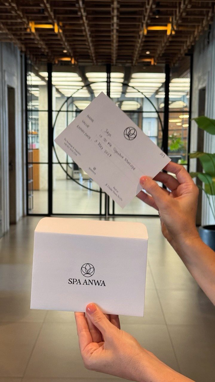 Hands holding a white spa gift voucher and a branded Spa Anwa box.