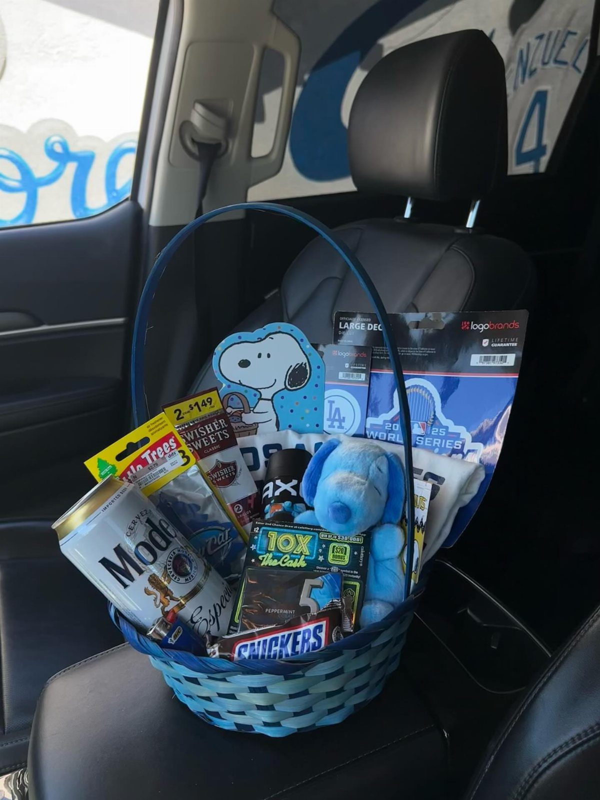 Blue woven Easter basket containing Modelo beer, candy, and a plush dog.