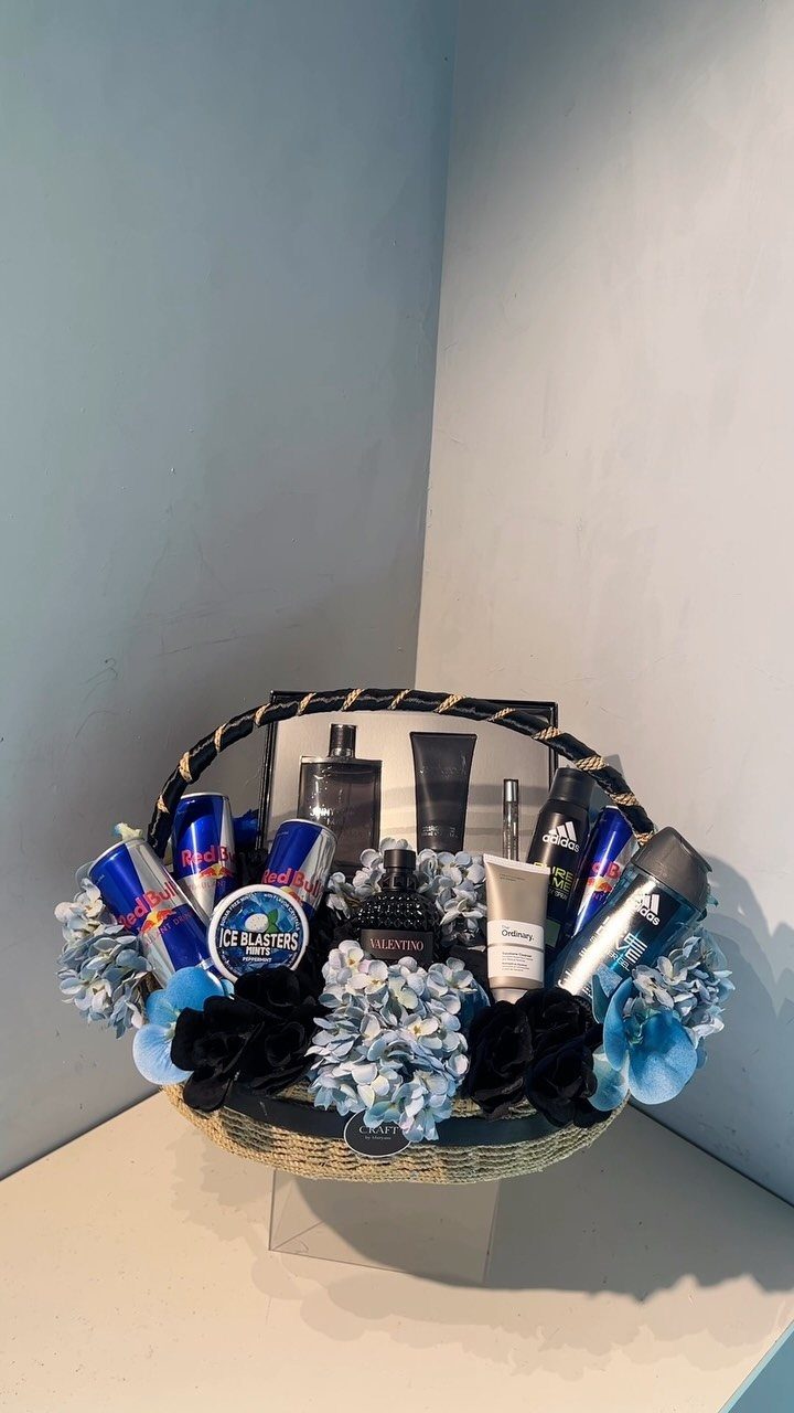 Wicker gift basket filled with blue and black grooming products and artificial flowers.