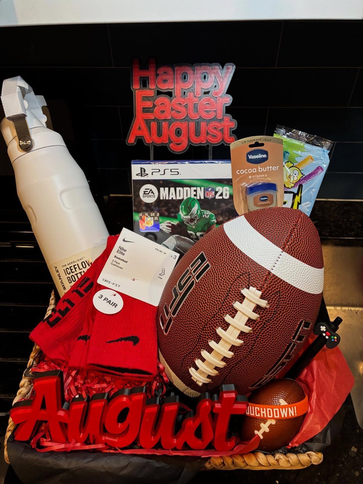 Easter basket containing a football, video game, water bottle, and red socks.