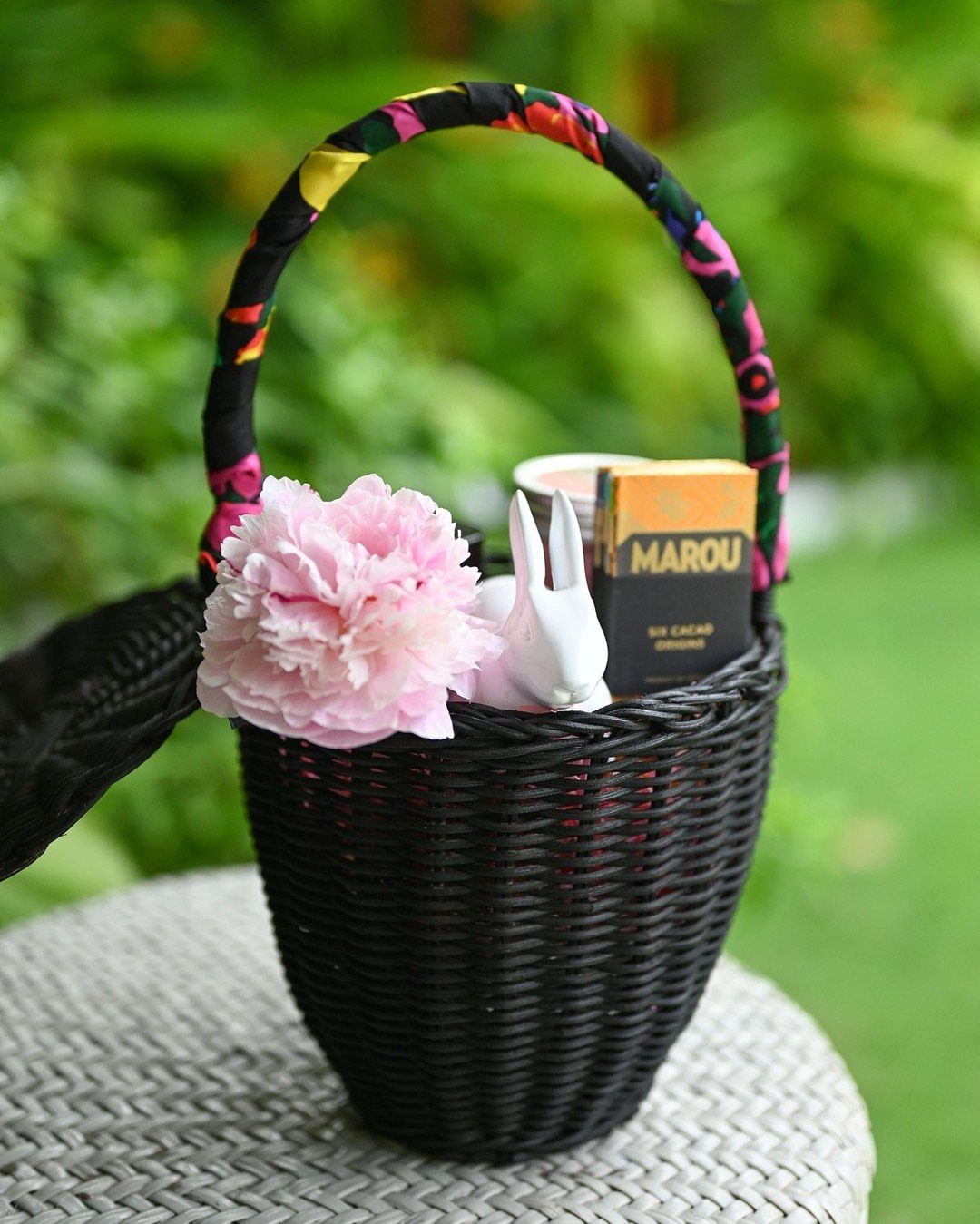 Black woven Easter basket with pink flower, white bunny, and chocolate bar.