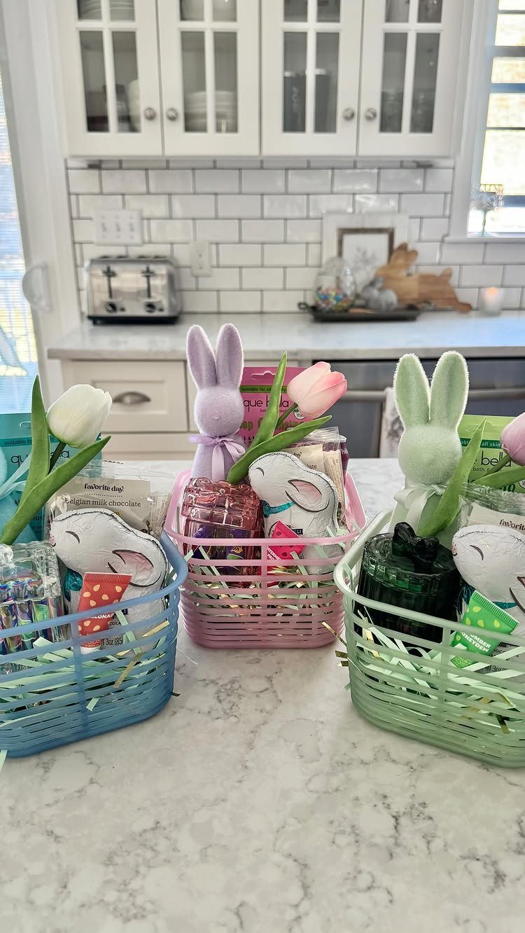 Three colorful Easter baskets filled with treats and flowers on a marble counter.