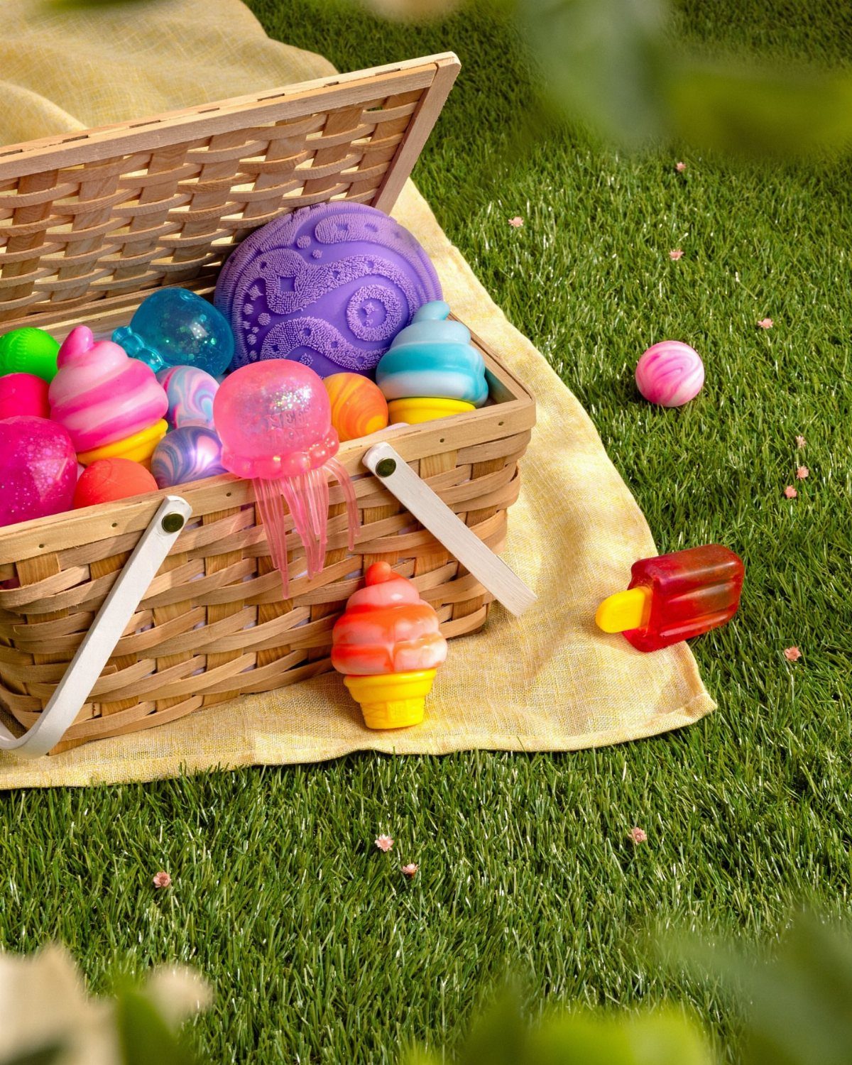 Wicker basket filled with colorful bath bombs on a cloth over green grass