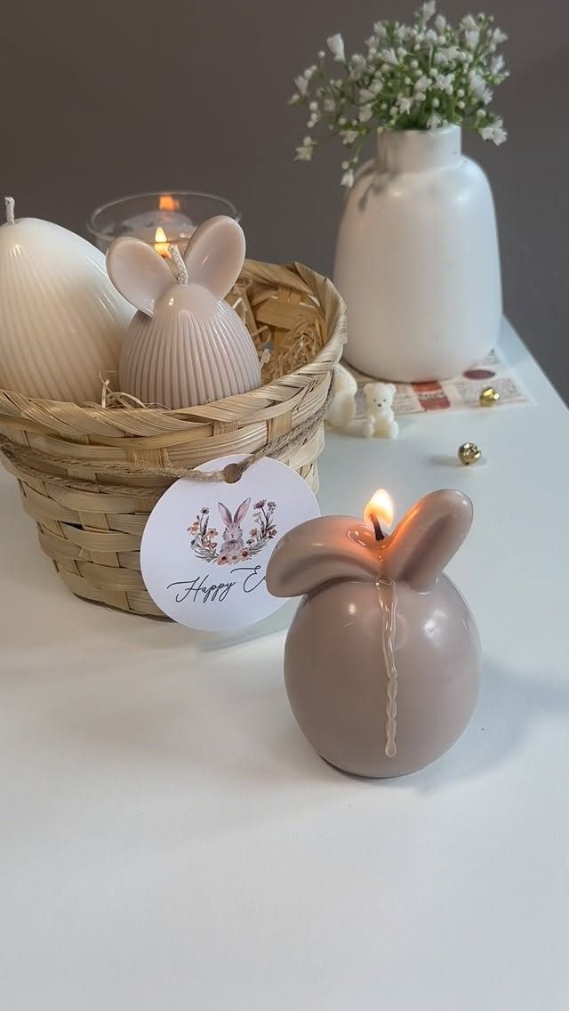 Woven Easter basket with bunny-shaped candles and a white vase of flowers.