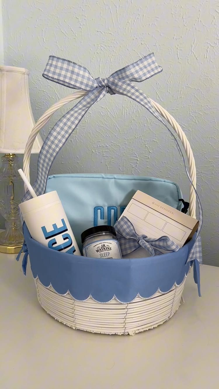 White wicker basket with blue accents containing a tumbler, pouch, and gift card.