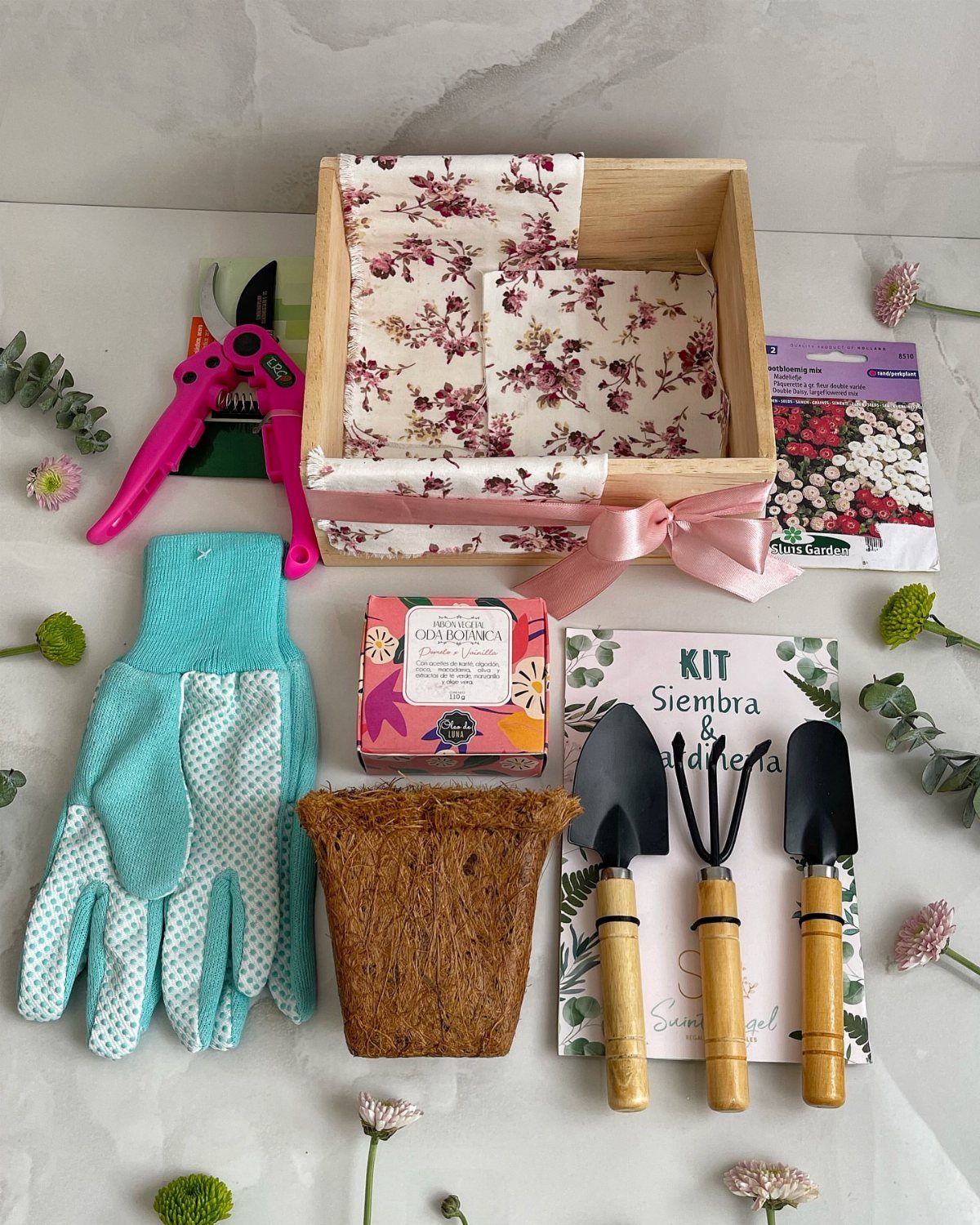 Gardening kit with wooden box, blue gloves, hand tools, and pink pruning shears.