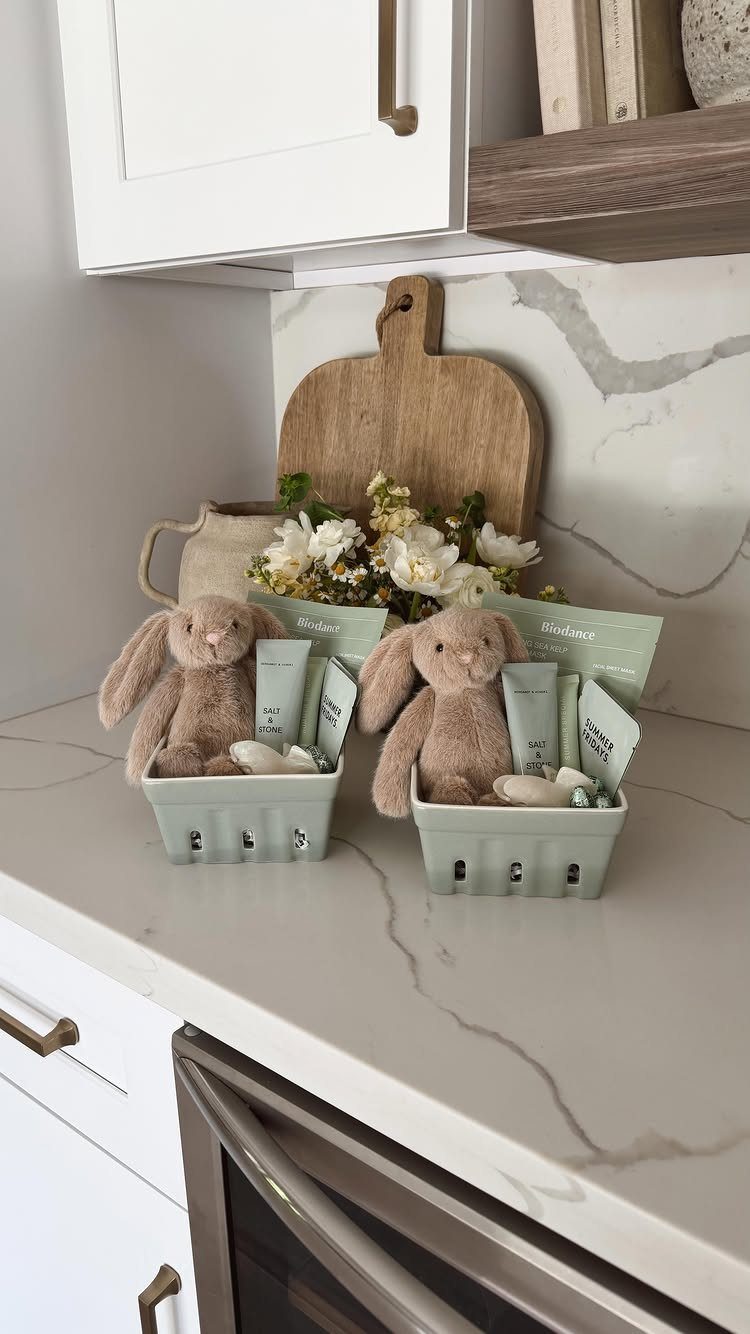 Two light green Easter baskets with plush bunnies and skincare on a marble counter.