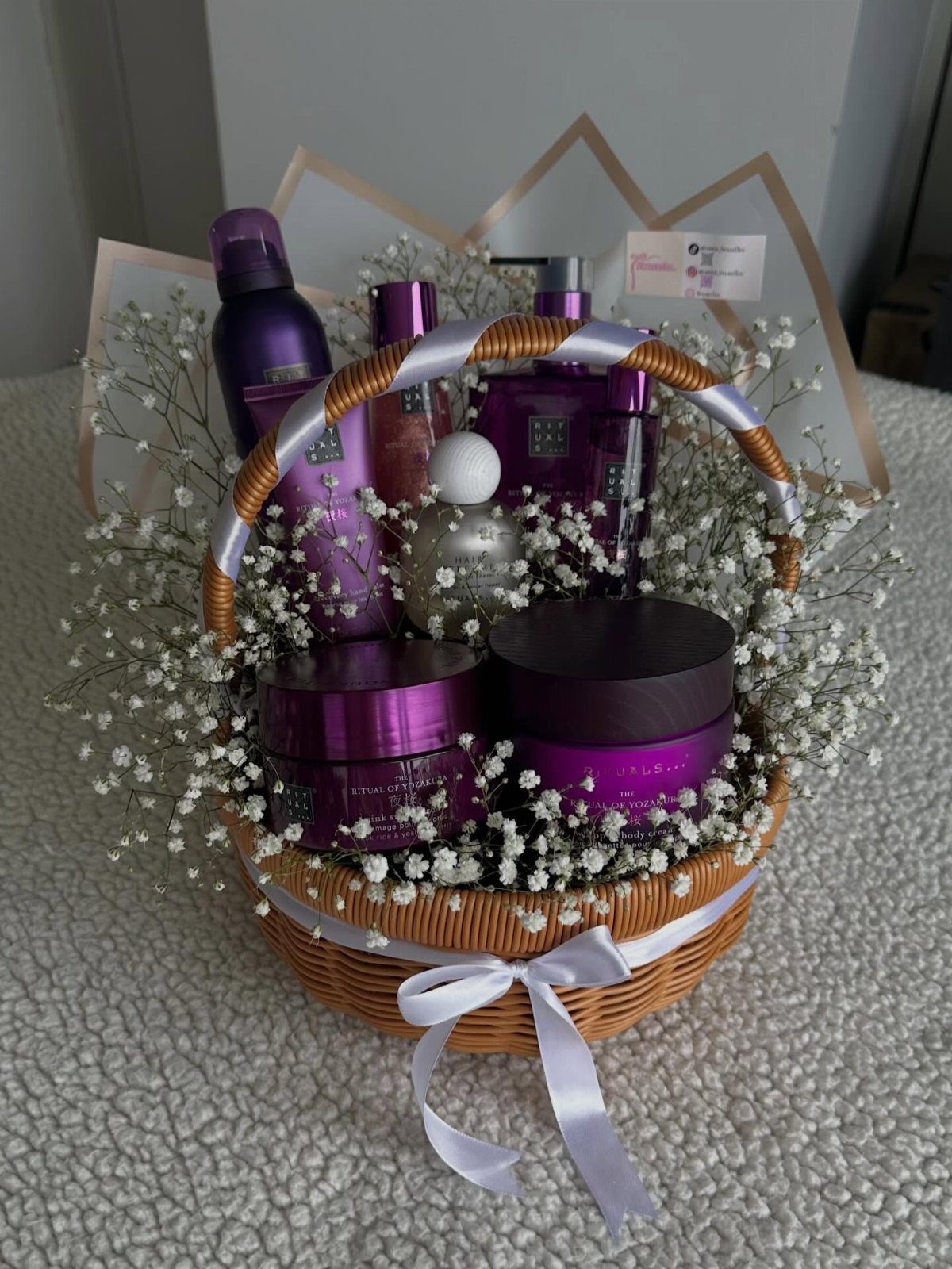 Wicker gift basket with purple skincare products and white baby's breath flowers.