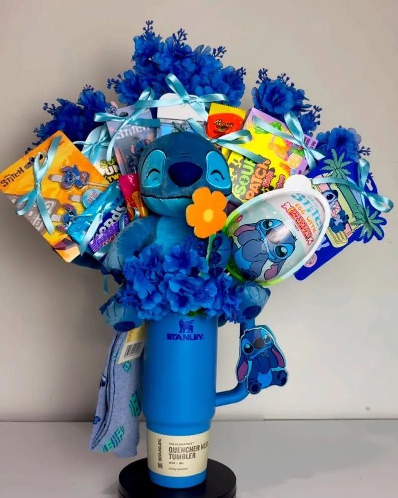 Blue Stanley tumbler gift basket filled with Stitch plush, snacks, and blue flowers.