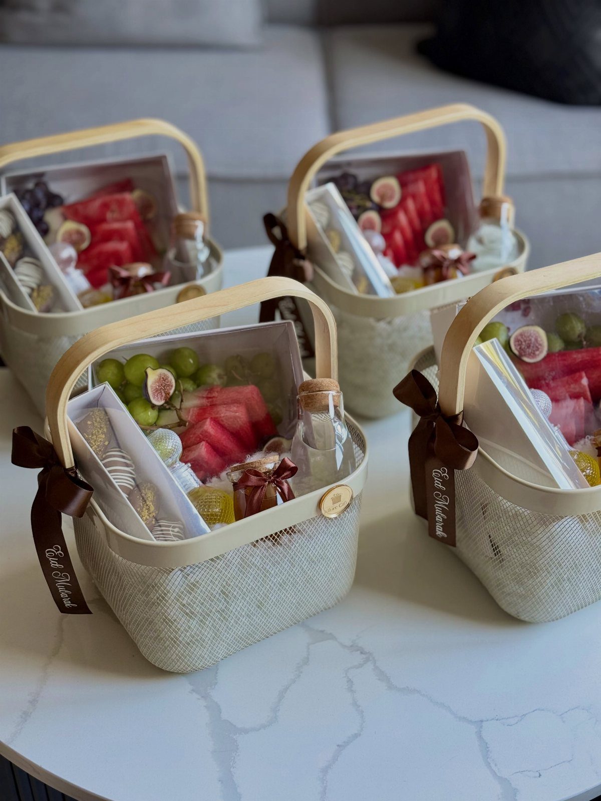 Four gourmet food baskets filled with fresh fruit, treats, and small bottles.