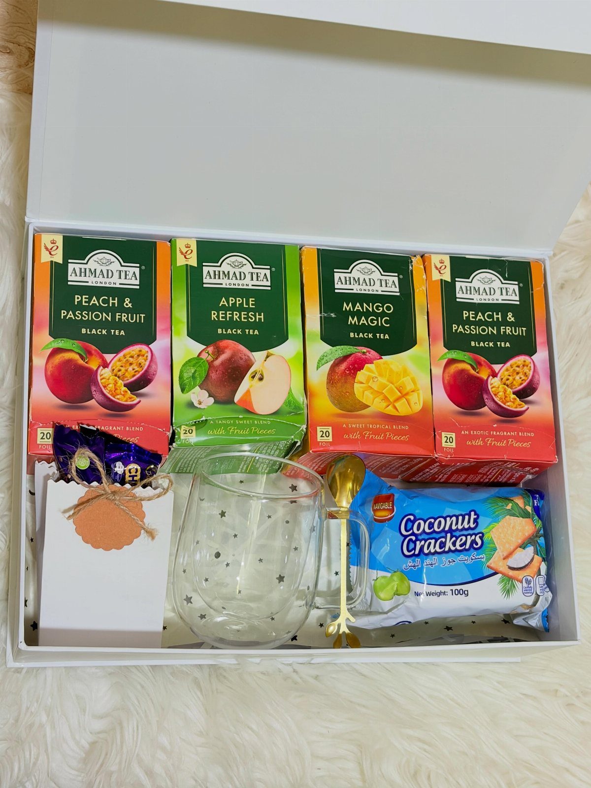Tea gift box with fruit tea boxes, glass mug, and coconut crackers.