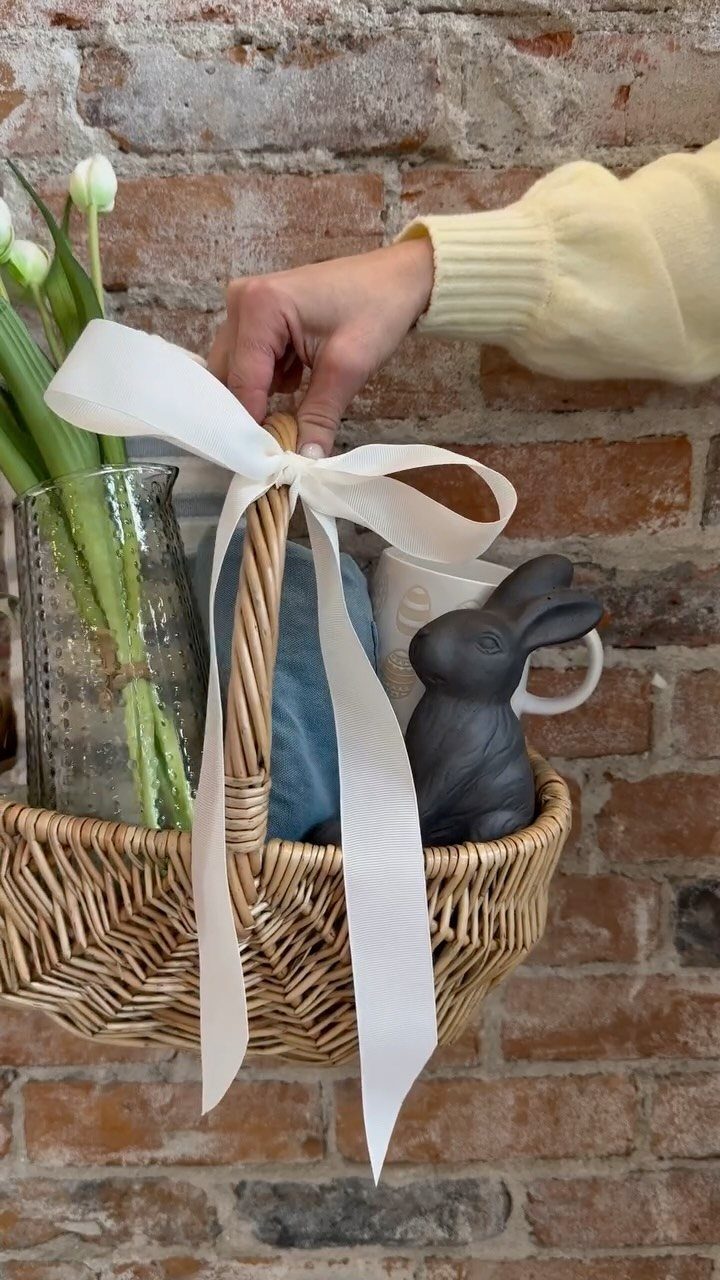 Woven wicker basket with white tulips, a white mug, and black bunny figurine.