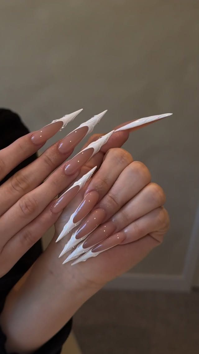 Almond shaped nails with nude base and sharp white jagged tips.