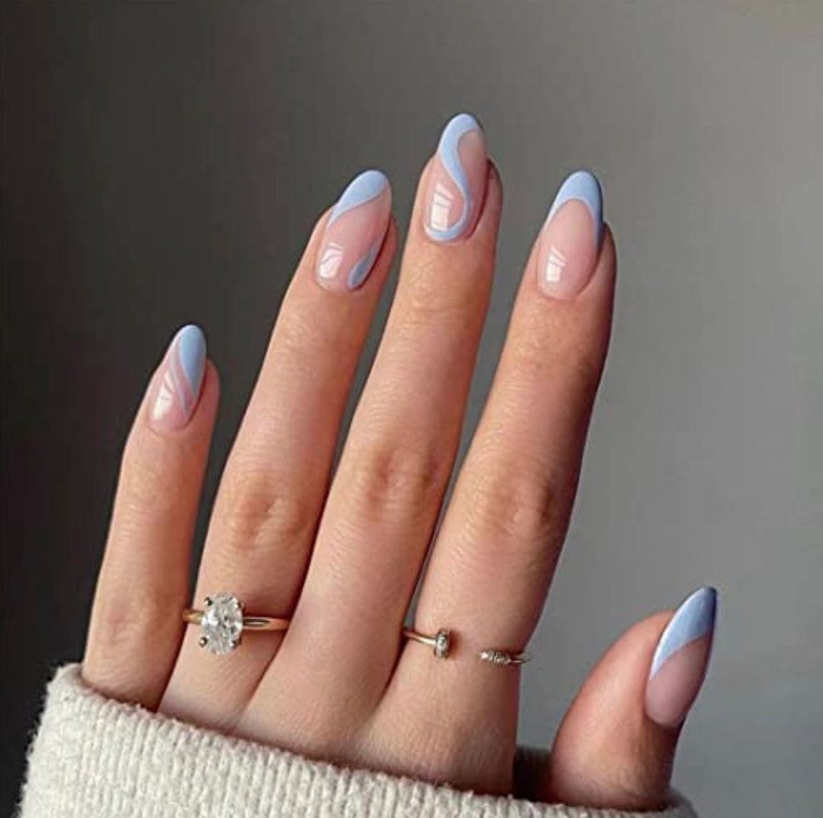 Almond shaped nails with nude base and light blue organic wavy line art.