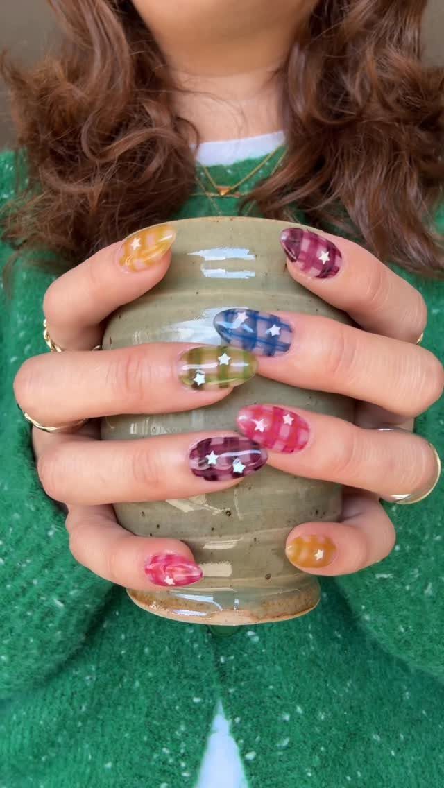 Pastel gingham patterned nails with white stars holding a brown ceramic vase.