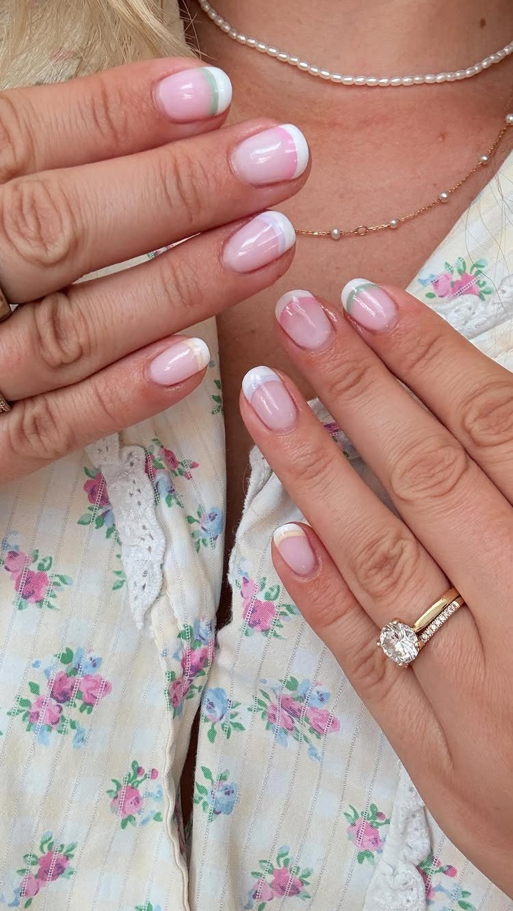 Hands with pastel French tip nails wearing a floral blouse and diamond ring