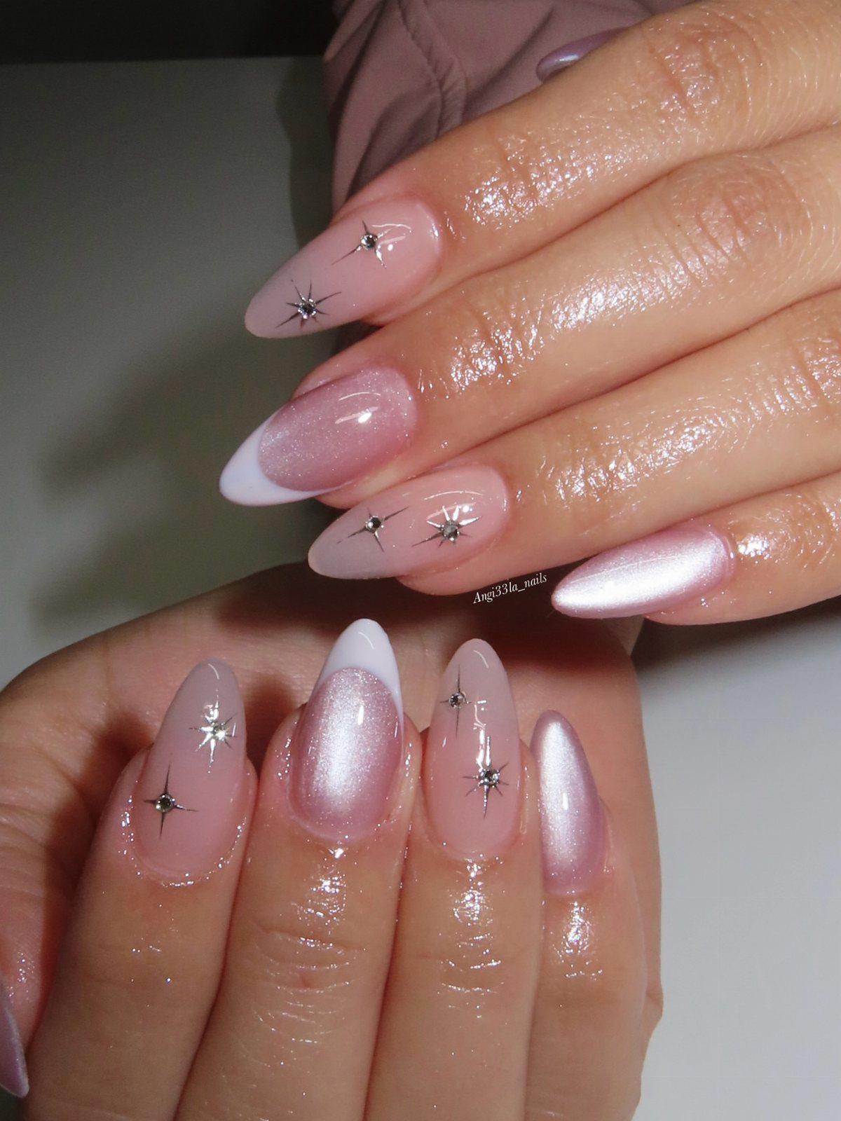 Nude almond nails decorated with small silver glitter stars and white French tips.