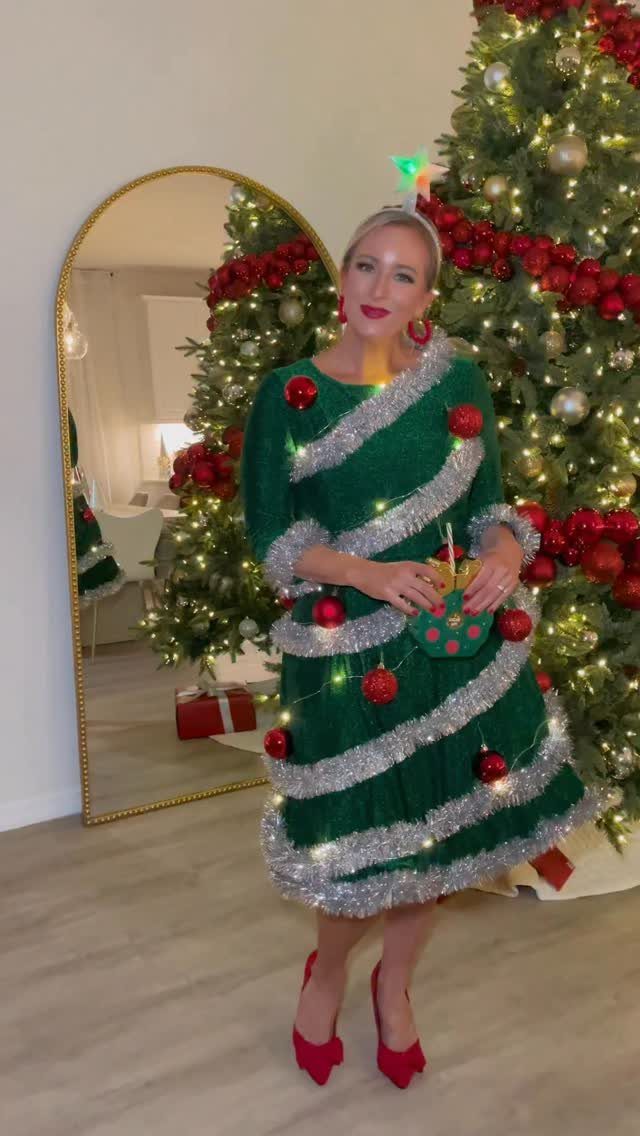 Woman wearing a green Christmas tree costume with silver tinsel and red ornaments.