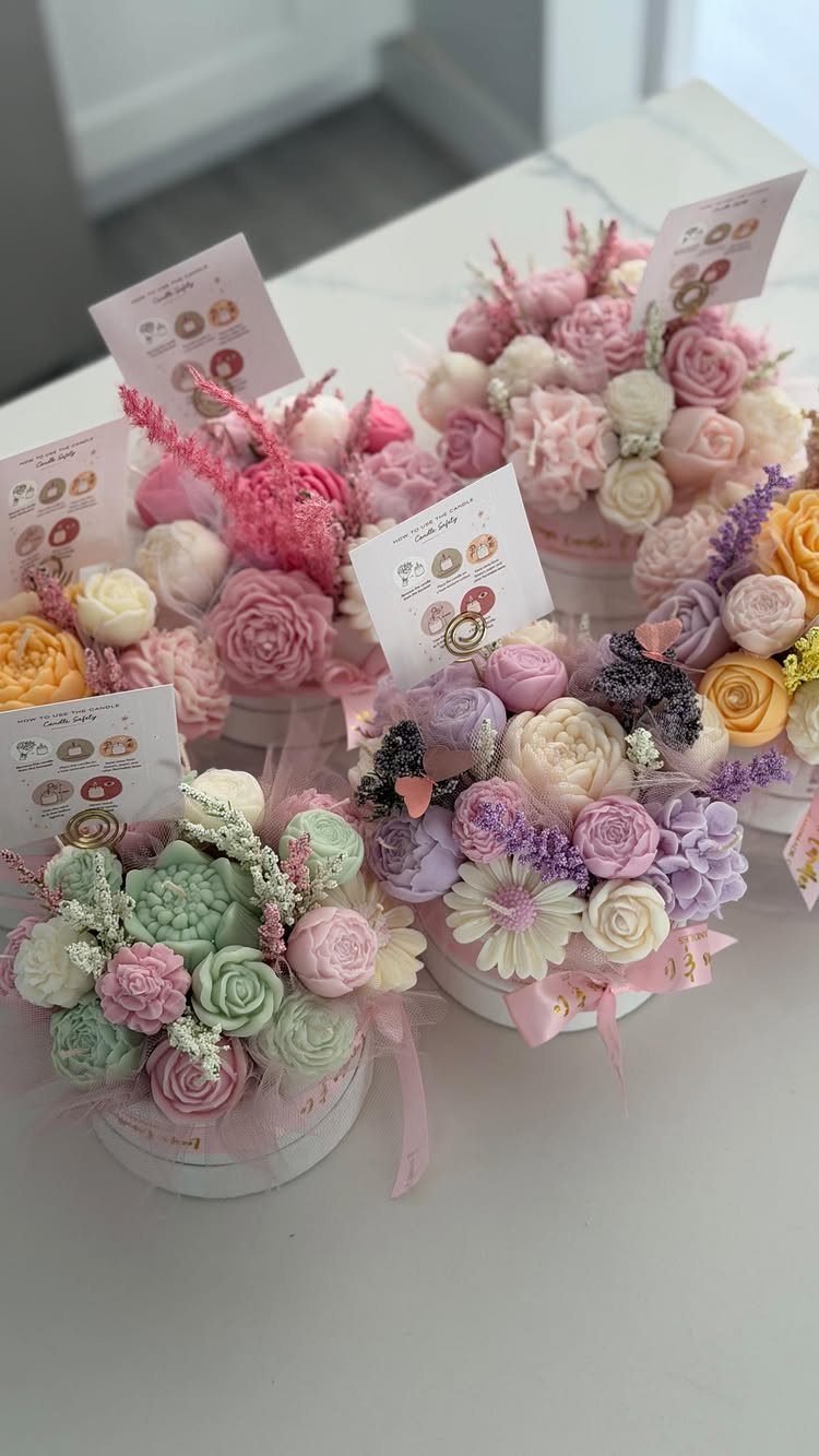 Pastel buttercream frosting flowers arranged in white round gift boxes on a table.