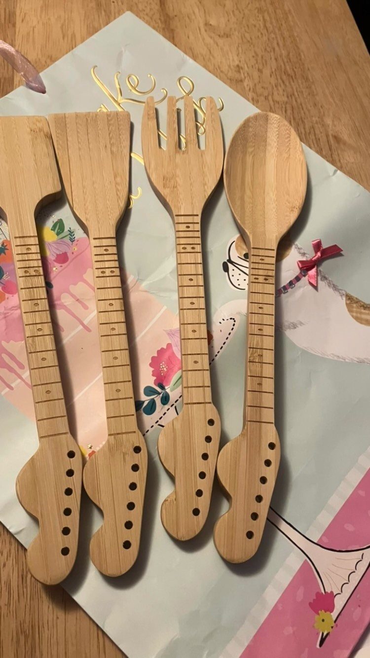 Wooden kitchen utensils shaped like electric guitars on decorative floral paper.