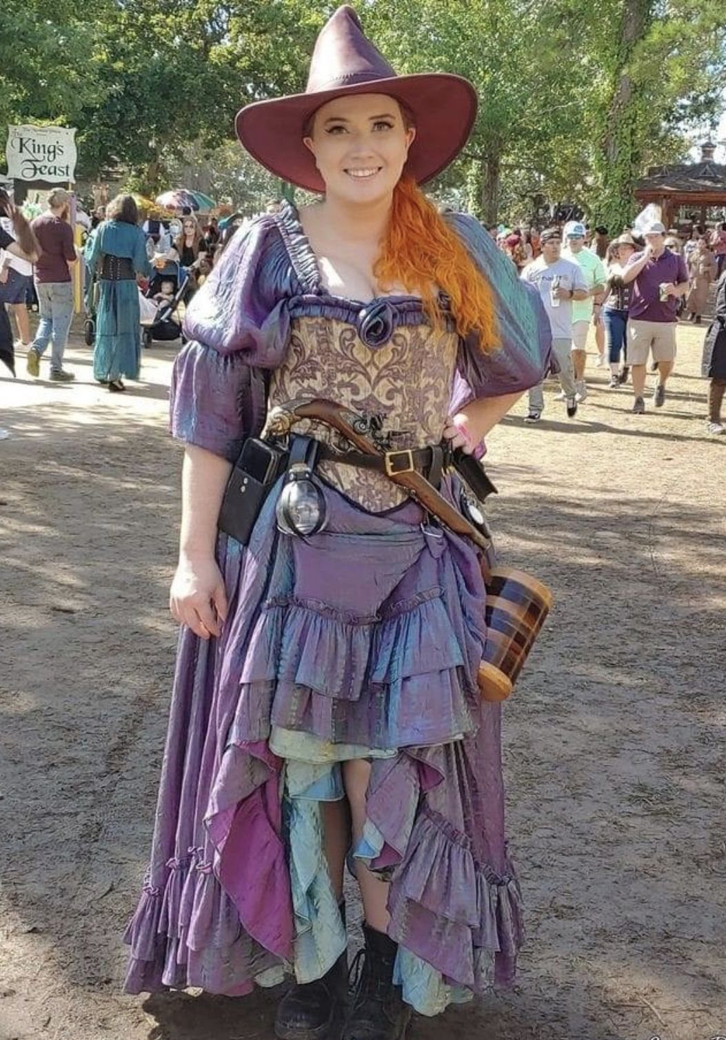 Woman in purple pointed witch hat and brown corset with iridescent purple dress