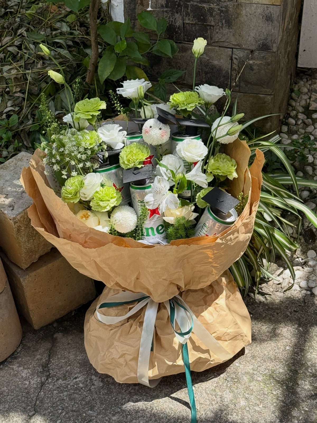 Beer bouquet with white and green flowers wrapped in brown kraft paper.
