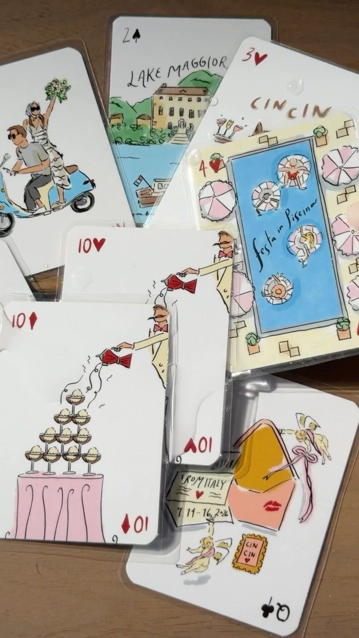 Custom playing cards with colorful hand-drawn illustrations scattered on a wooden table.