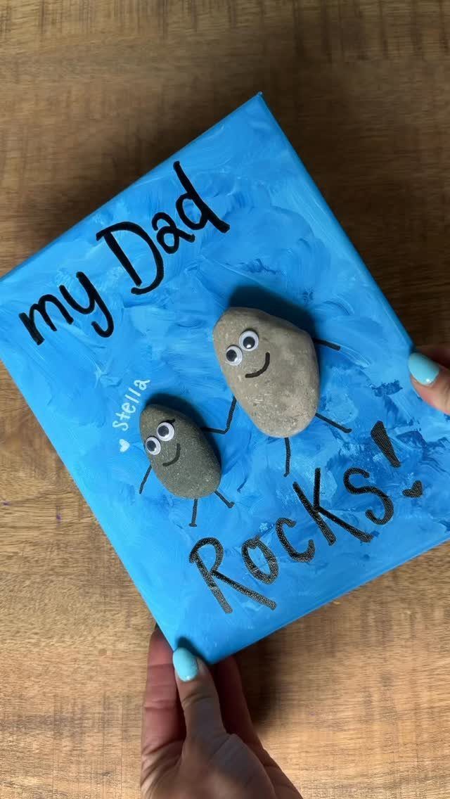 Blue painted canvas with two decorated stones and the text my Dad Rocks!