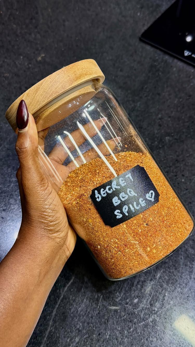 Glass jar filled with orange BBQ spice rub and a handwritten label.