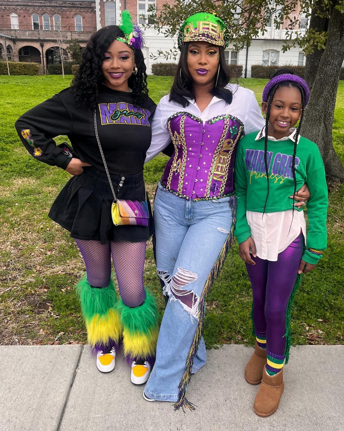 Three family members posing in purple, green, and gold Mardi Gras themed outfits.