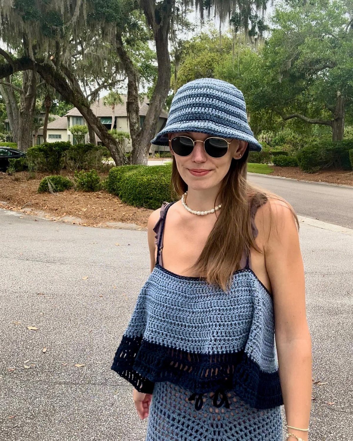 Woman wearing a blue crochet cover-up dress and matching bucket hat outdoors.