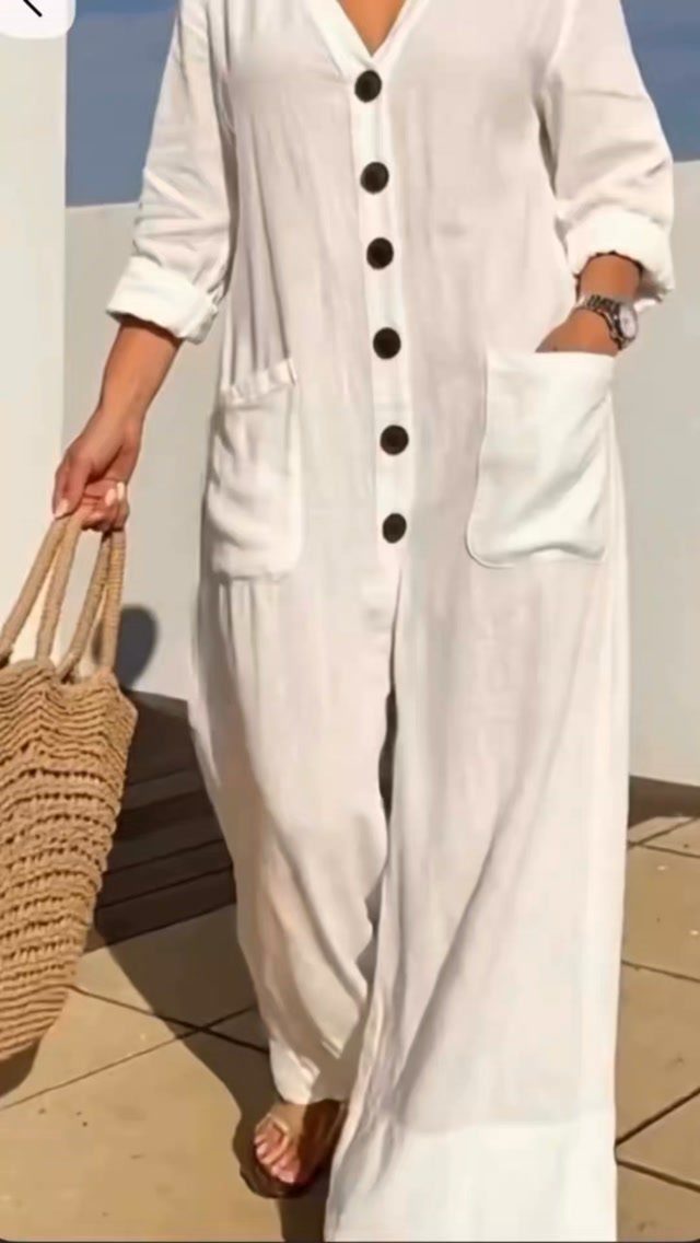 Woman wearing a white linen jumpsuit with buttons and carrying a straw bag.