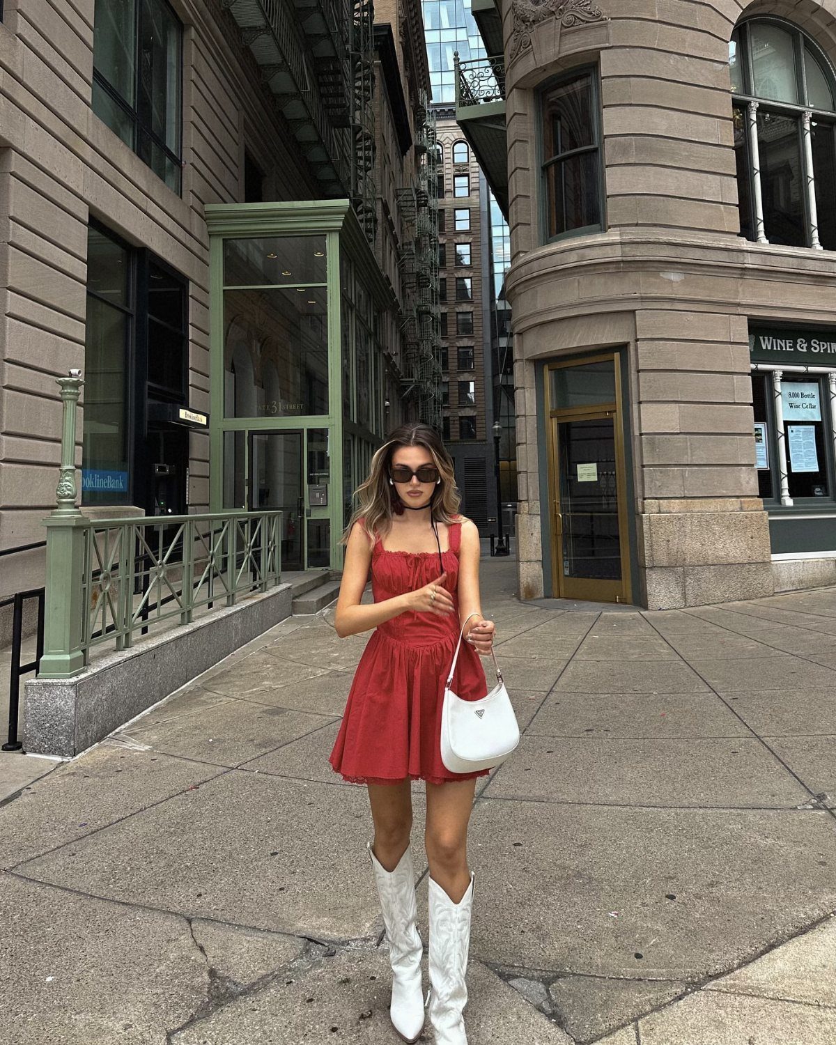 Woman in a short red dress and white cowboy boots on a city street