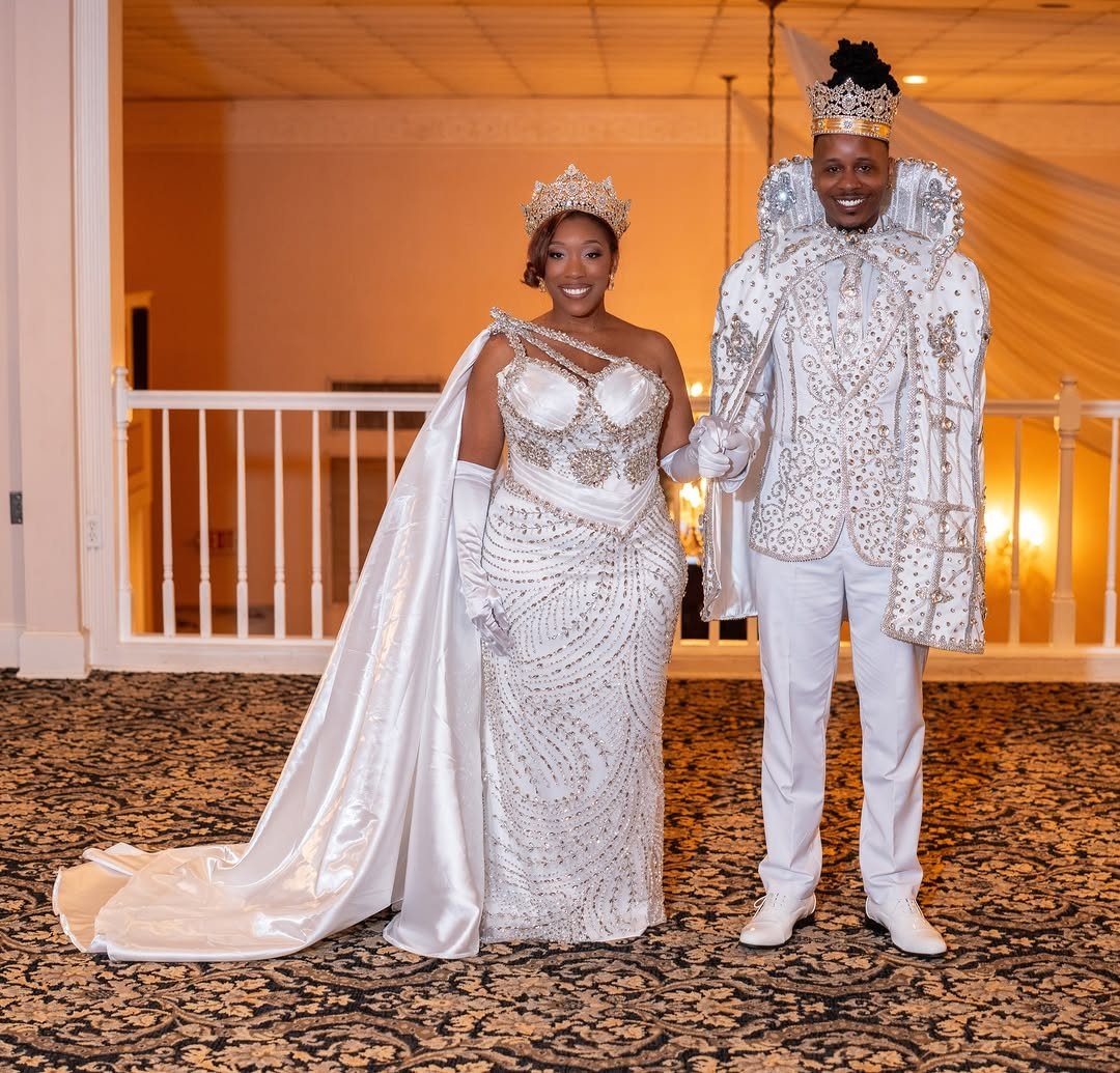 Couple in ornate white formal wear, woman wearing white elbow length satin gloves.